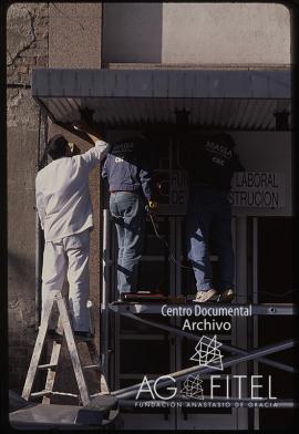 Obreros colocando el cartel de la Fundación Laboral de la Construcción