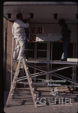 Obreros colocando el cartel de la Fundación Laboral de la Construcción