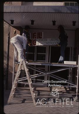 Obreros colocando el cartel de la Fundación Laboral de la Construcción