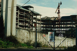 Edificios en construcción con un cartel en la valla sobre el 27-E, Huelga general