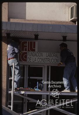 Obreros colocando el cartel de la Fundación Laboral de la Construcción