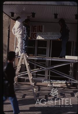 Obreros colocando el cartel de la Fundación Laboral de la Construcción